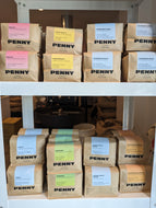 Packs of Penny Coffee on a shelf with colorful labels.